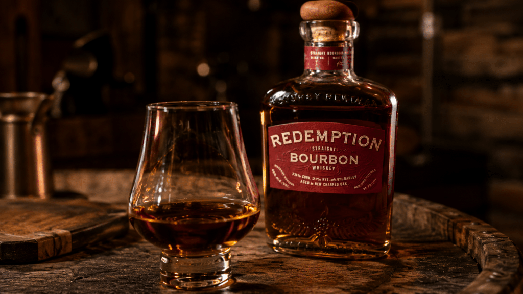 Glass of Redemption Bourbon poured neat beside the bottle