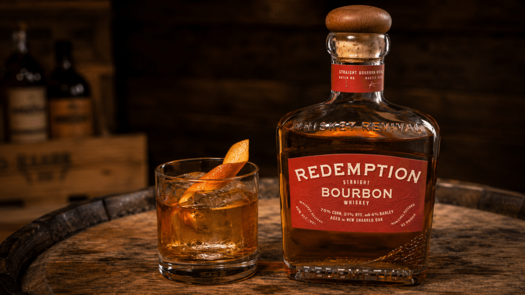 Redemption Bourbon bottle beside an Old Fashioned cocktail with orange peel