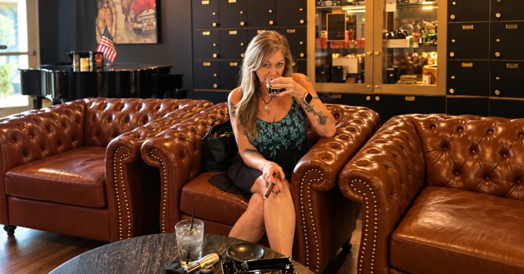Gina sipping espresso while holding a cigar in Jallo’s leather lounge seating.